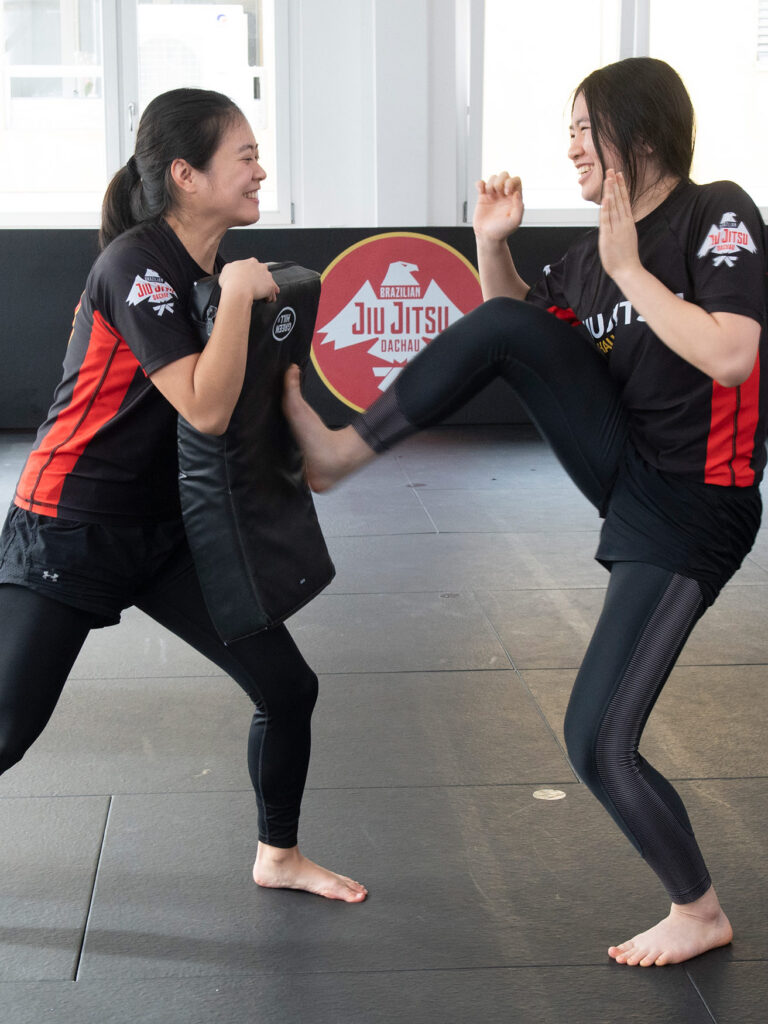 Zwei Frauen trainieren Krav Maga mit Schlagpolster in einer freundlichen und entspannten Atmosphäre.