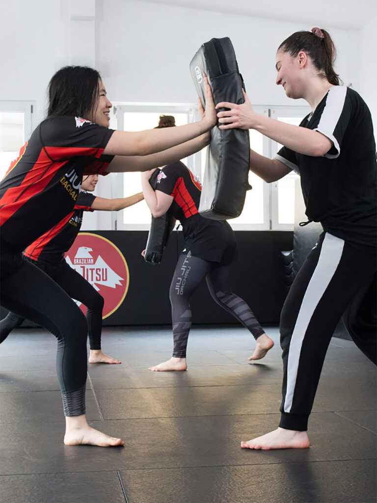 Zwei Frauen trainieren Krav Maga für Anfänger mit Schlagpolster in einer entspannten Trainingsatmosphäre.